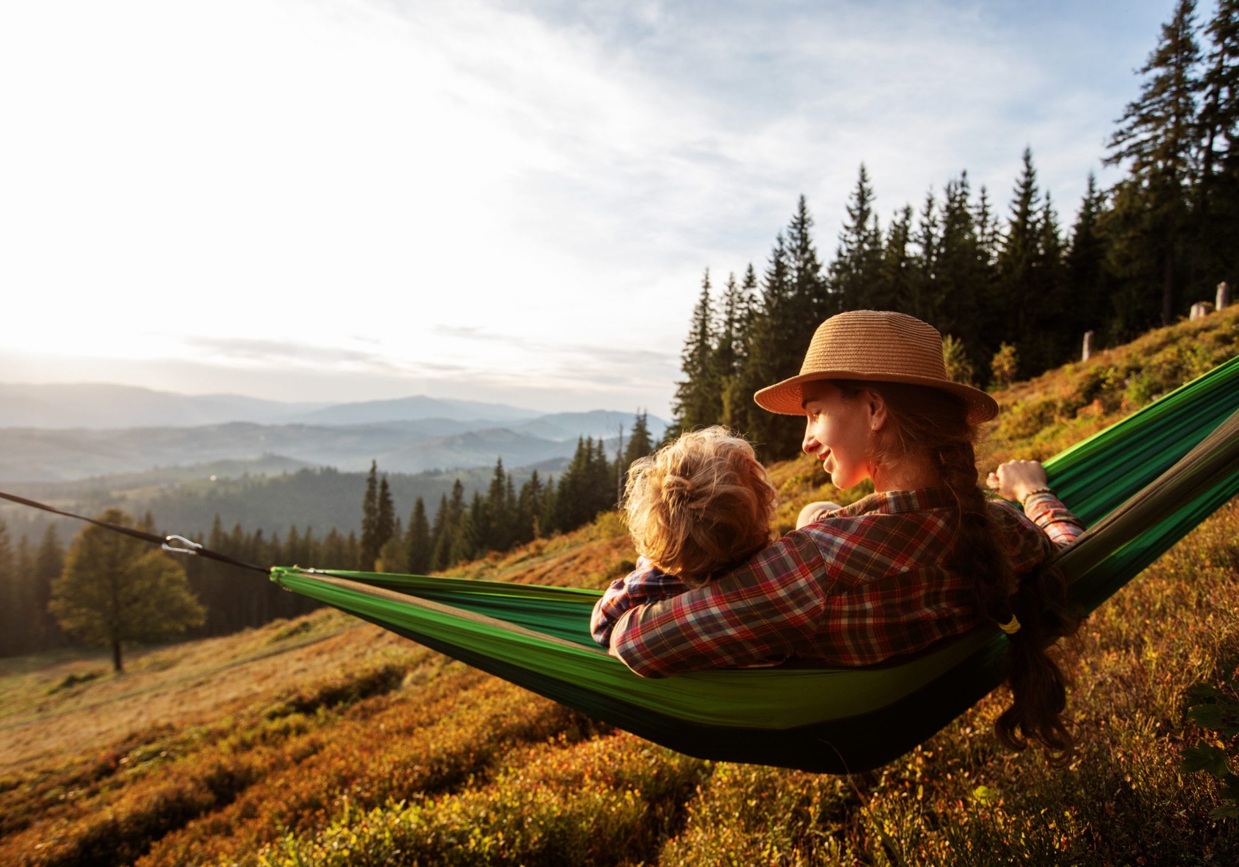 Boy tourist resting in a hammock in the mountains at sunset